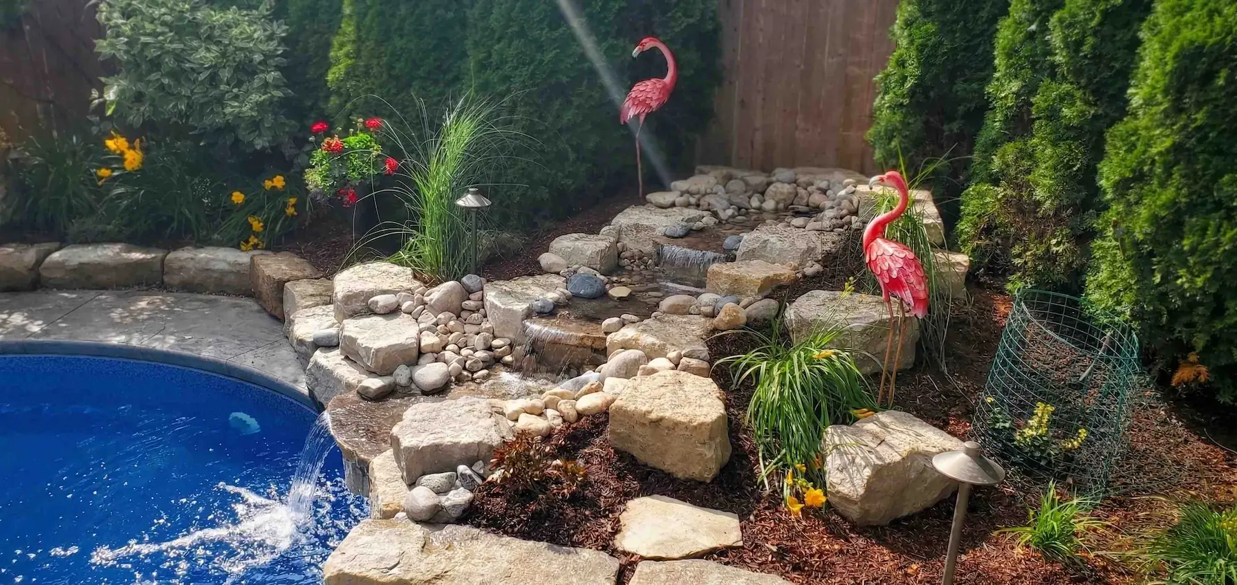 Backyard pond and waterfall installation with planted edges and structured stonework